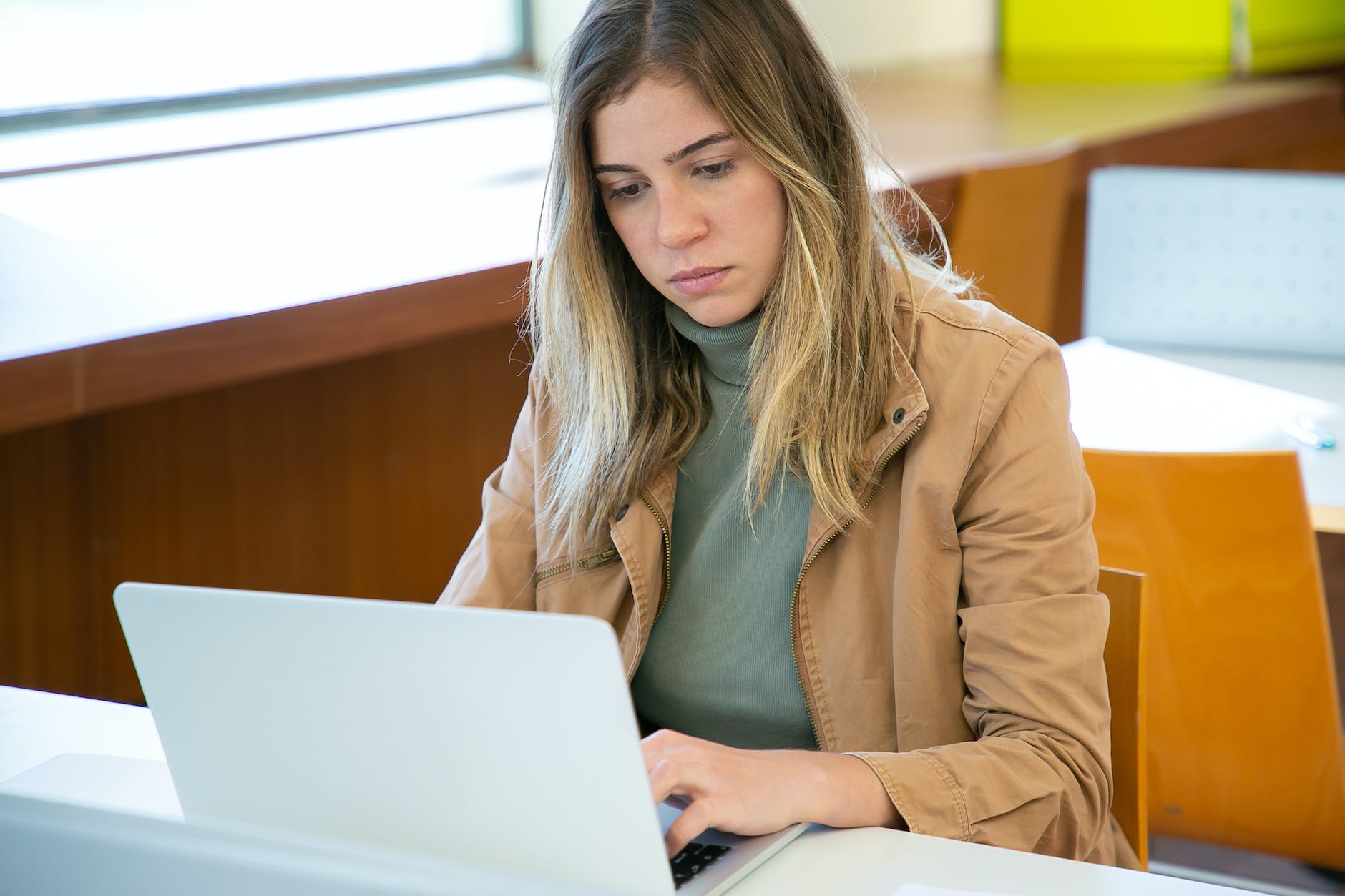 serious woman working on laptop in library